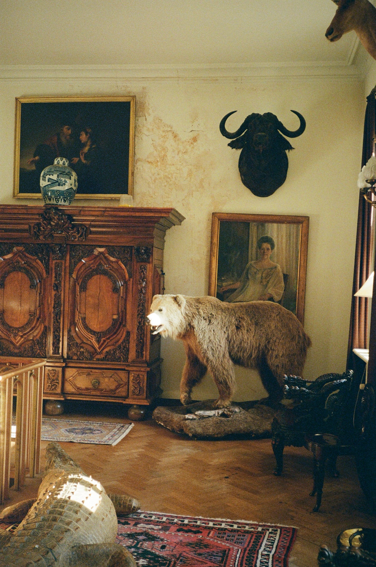 A grand interior with a carved wooden cabinet, oil paintings and a standing bear