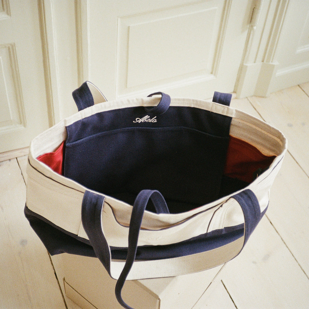 Babette's Travel Bag open, showing the navy interior pocket with Abelo embroidery