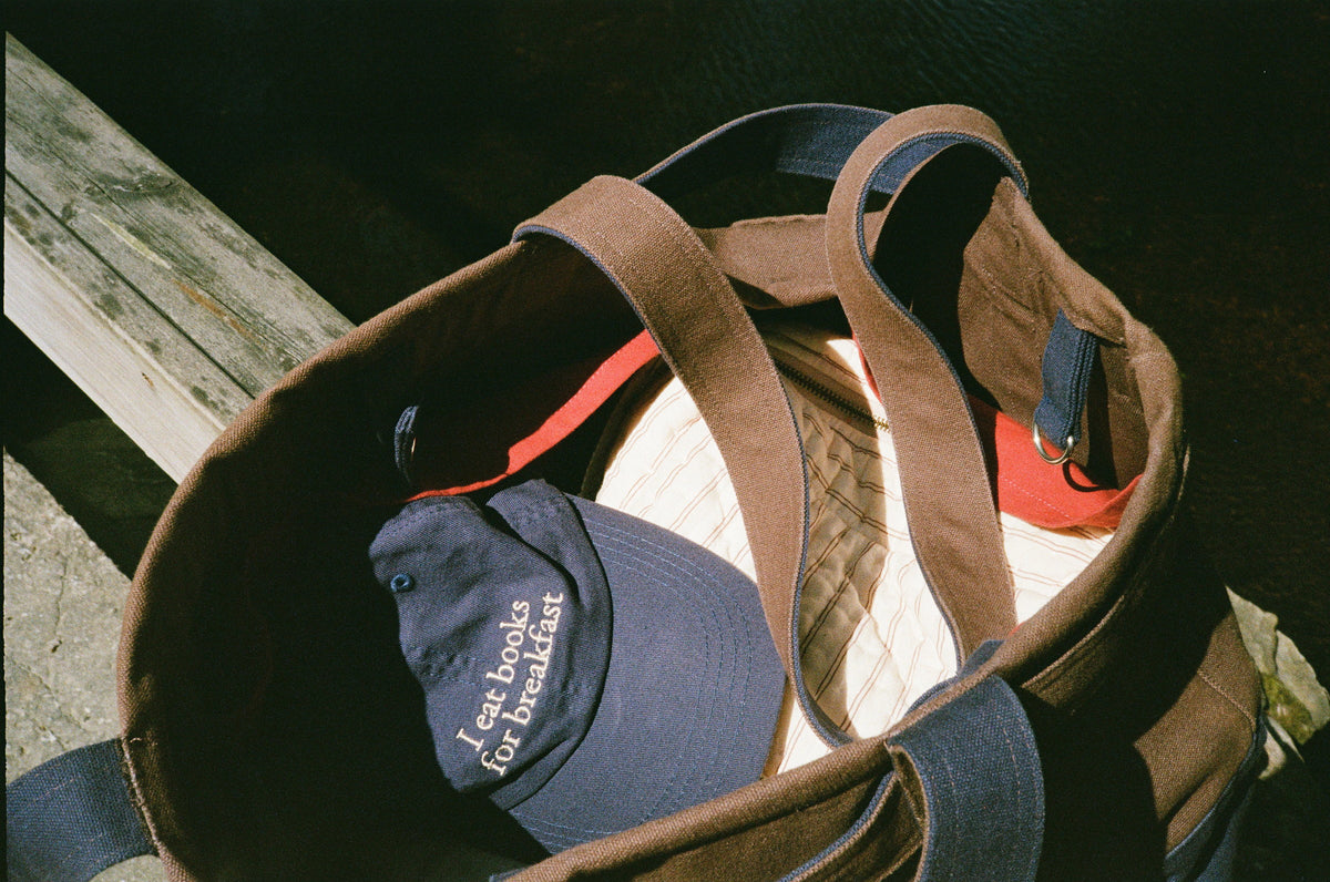 An open Abelo bag with a navy cap reading I eat books for breakfast