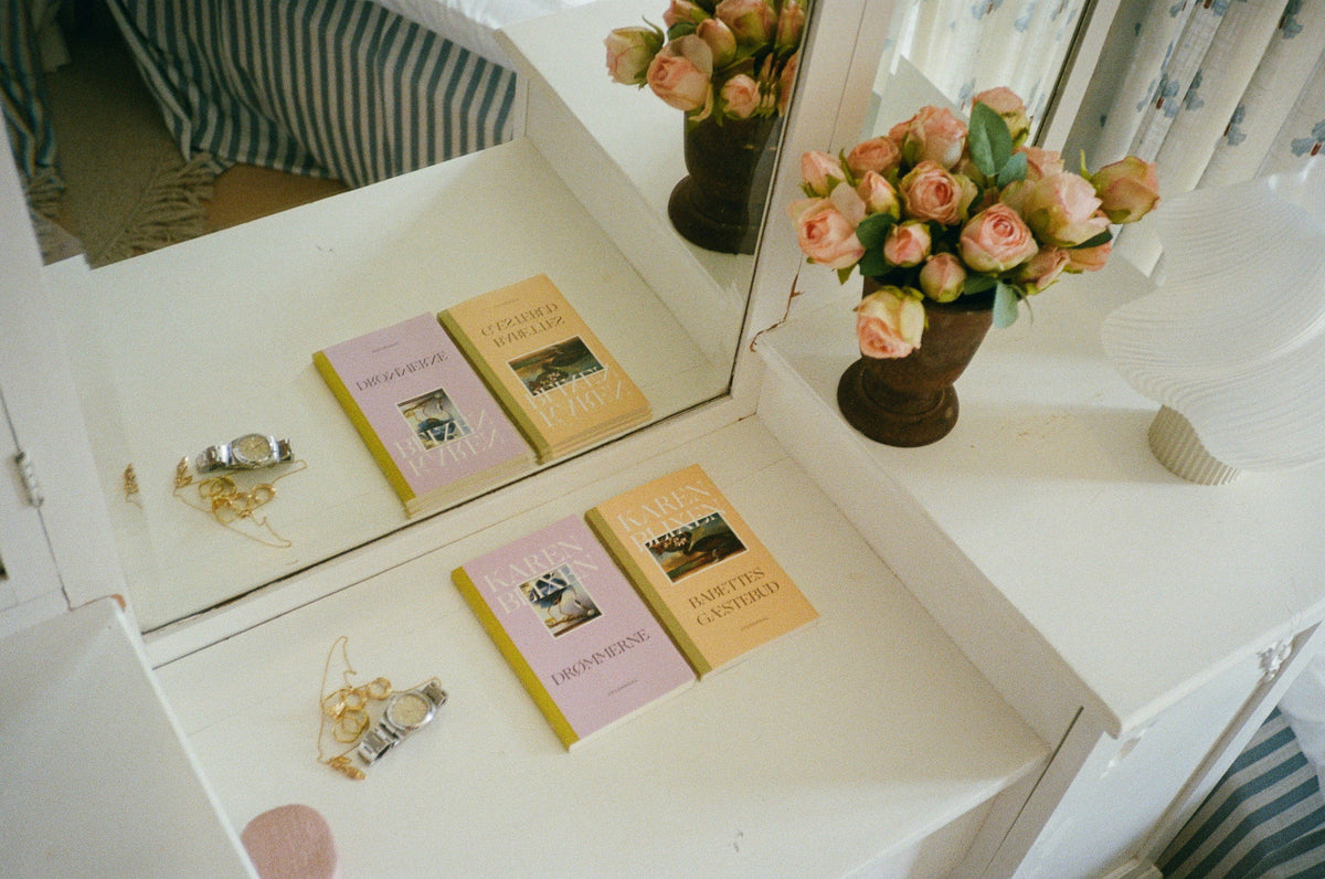 Karen Blixen novels and pink roses on a white dressing table